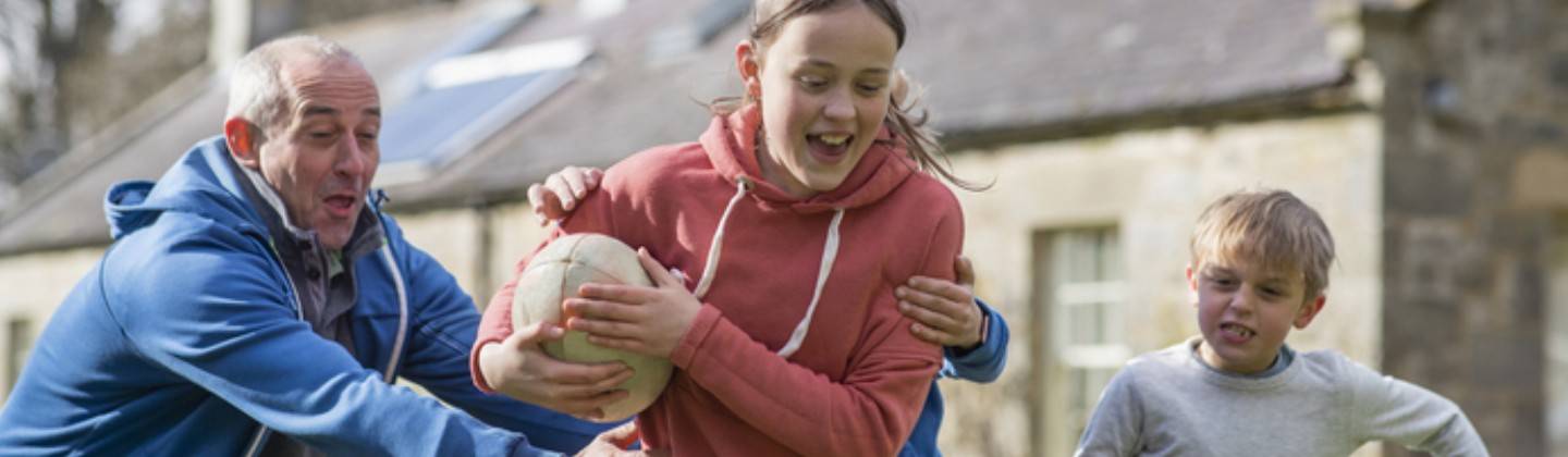 Adulto jugando con dos niños balonmano