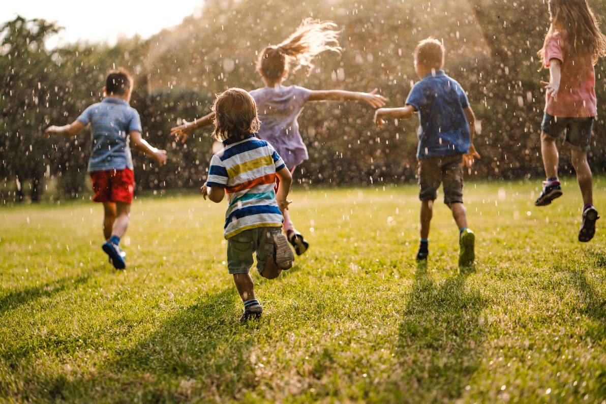 Niños corriendo de espaldas mientras llueve