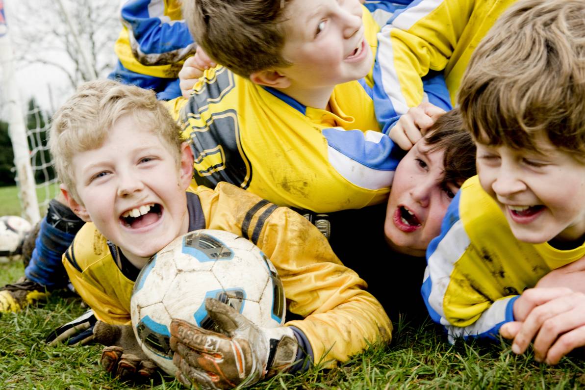 Niños jugando fútbol y sonriendo