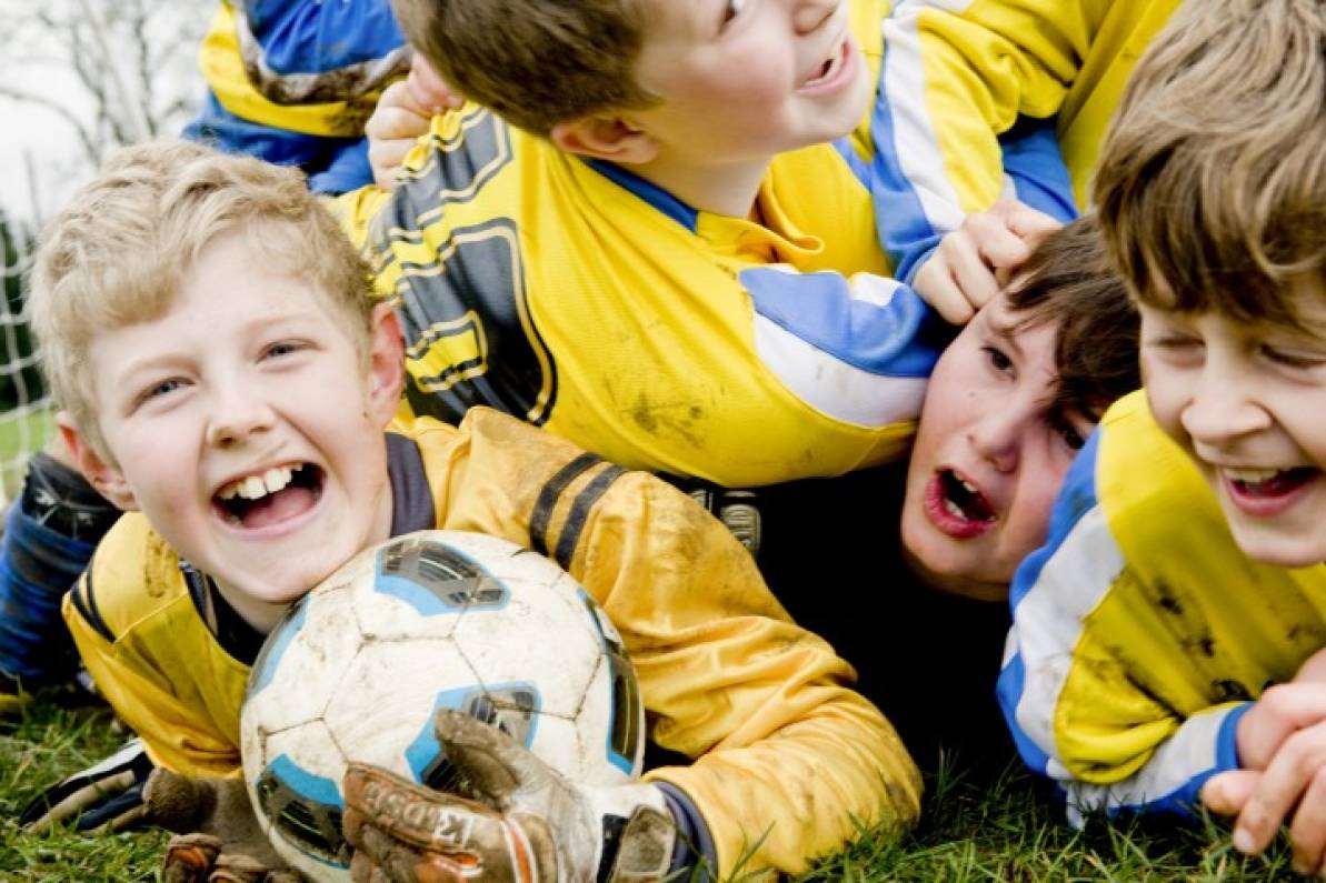 Niños jugando con un balón y sonriendo