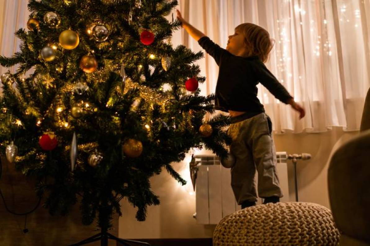 Niño colocando las manualidades navideñas en el árbol